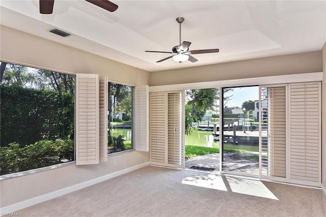 empty room featuring light colored carpet, a raised ceiling, and ceiling fan