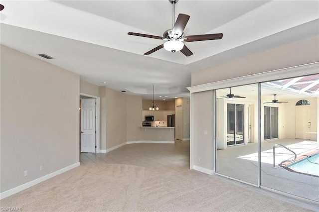 carpeted empty room featuring ceiling fan with notable chandelier