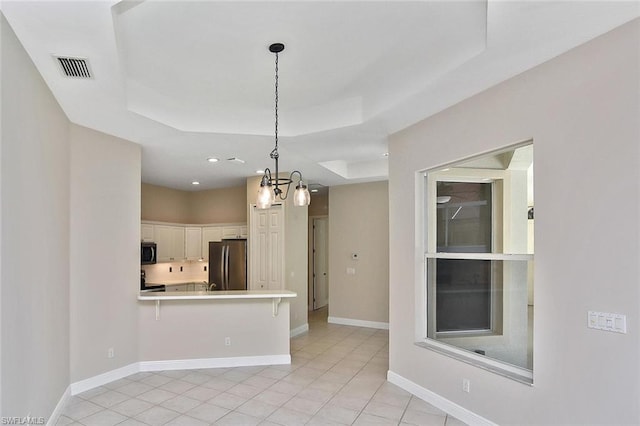 interior space featuring light tile floors, a chandelier, and a tray ceiling