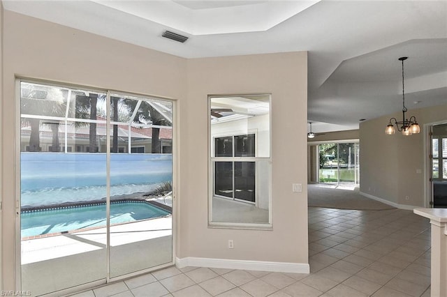 entryway featuring a tray ceiling, a notable chandelier, and light tile floors