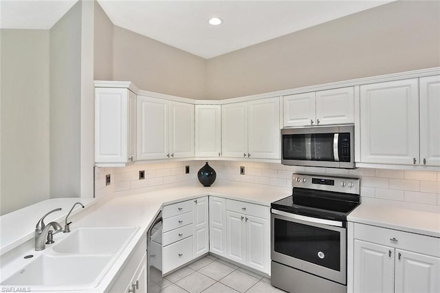 kitchen featuring sink, stainless steel appliances, light tile floors, white cabinets, and tasteful backsplash