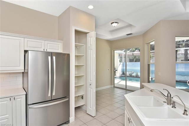 kitchen featuring white cabinetry, stainless steel fridge, sink, light tile floors, and tasteful backsplash