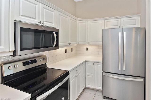 kitchen featuring light tile flooring, tasteful backsplash, appliances with stainless steel finishes, and white cabinetry