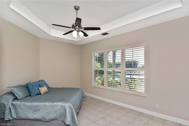 tiled bedroom with a raised ceiling and ceiling fan