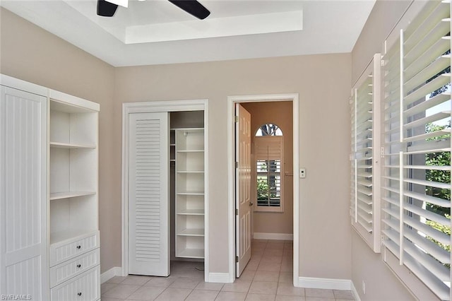 tiled bedroom with a raised ceiling and ceiling fan