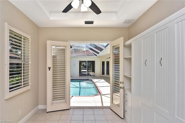 interior space featuring a tray ceiling, ceiling fan, and light tile flooring