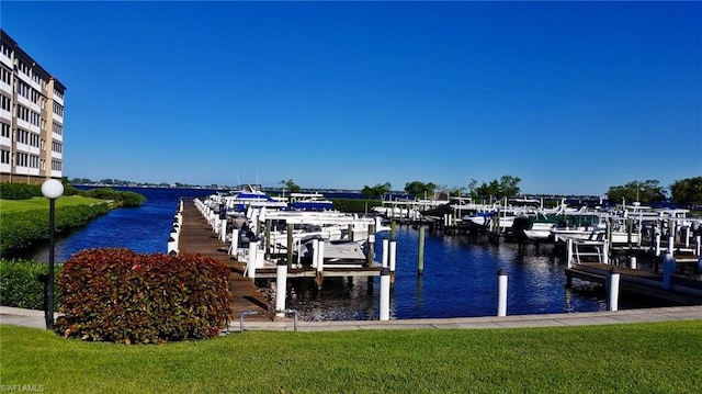 view of dock with a lawn and a water view