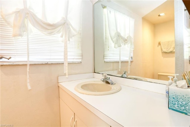 bathroom with toilet, a healthy amount of sunlight, and large vanity