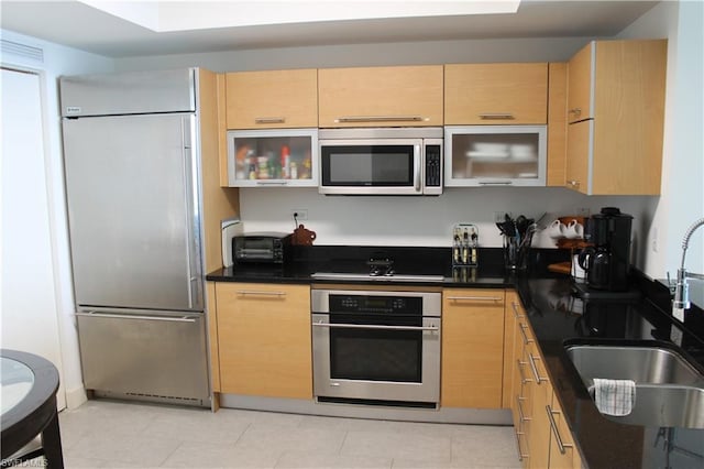 kitchen with light tile floors, appliances with stainless steel finishes, light brown cabinets, and sink