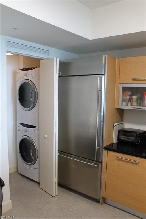 washroom featuring stacked washer / drying machine and light tile flooring