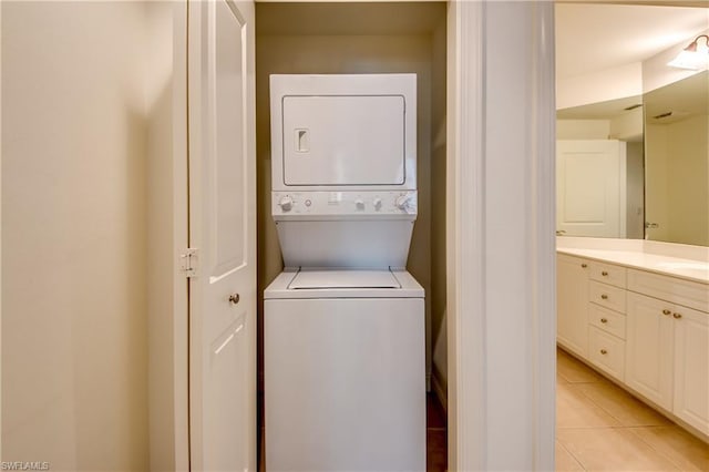 laundry area featuring stacked washer / dryer and light tile floors