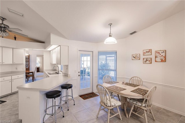 dining room with lofted ceiling, ceiling fan, light tile floors, and sink