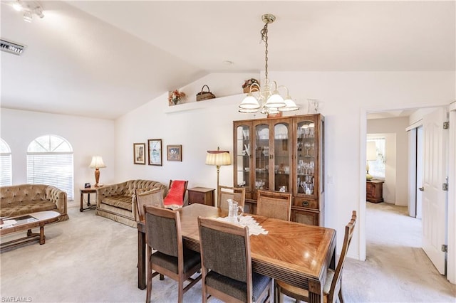 dining area with light colored carpet, vaulted ceiling, and an inviting chandelier