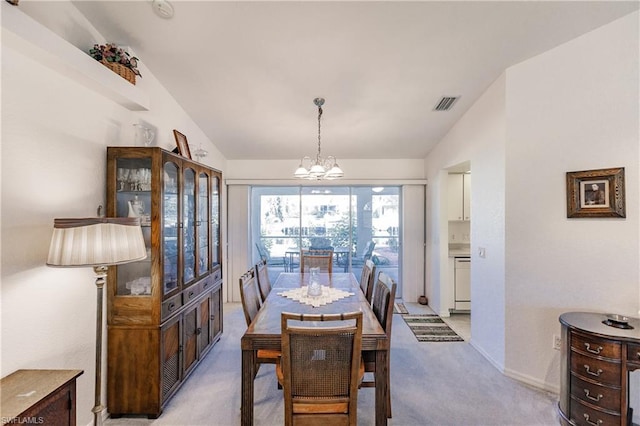 carpeted dining area with an inviting chandelier and lofted ceiling