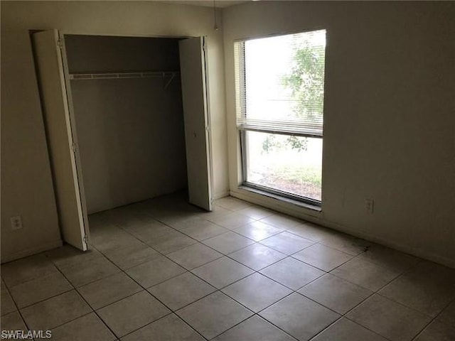 unfurnished bedroom featuring a closet and light tile flooring