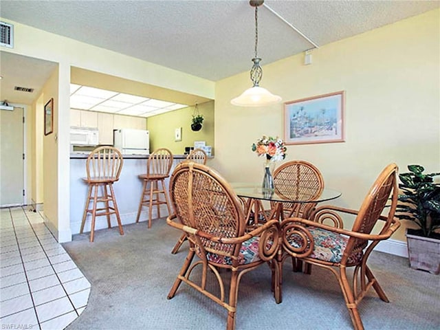 tiled dining room with a textured ceiling