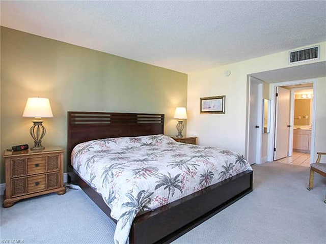 carpeted bedroom featuring ensuite bath and a textured ceiling