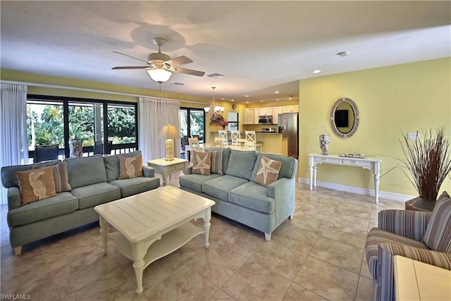 living room with light tile flooring, a healthy amount of sunlight, french doors, and ceiling fan with notable chandelier