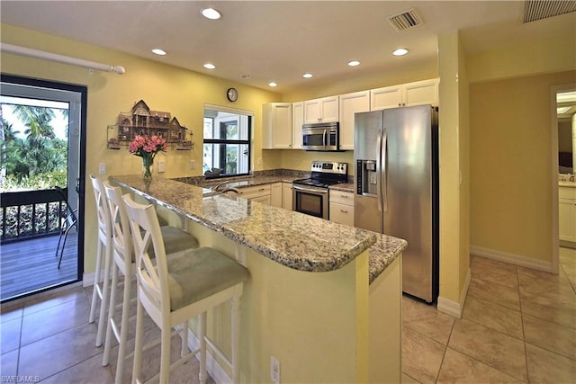 kitchen featuring light tile floors, kitchen peninsula, stainless steel appliances, and light stone countertops