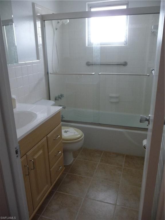 full bathroom featuring tile floors, shower / bath combination with glass door, toilet, and vanity