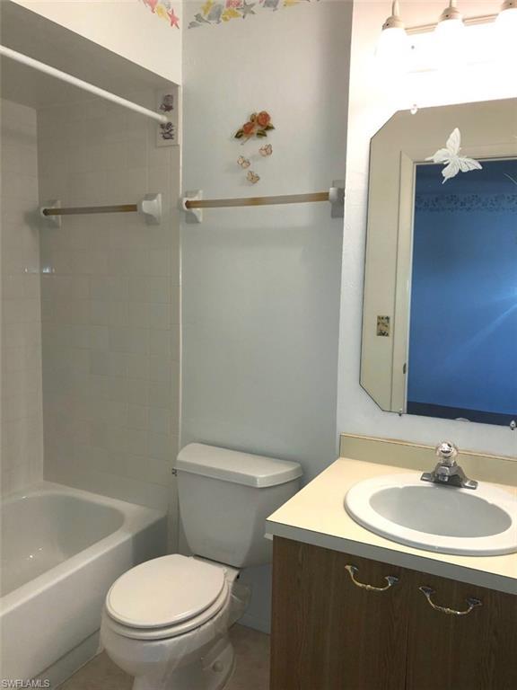 full bathroom with tiled shower / bath, toilet, and vanity