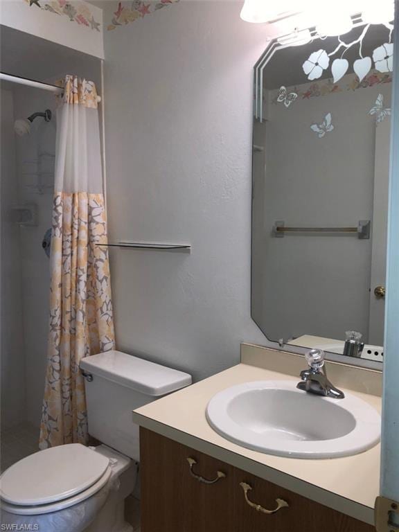 bathroom featuring toilet, curtained shower, and vanity