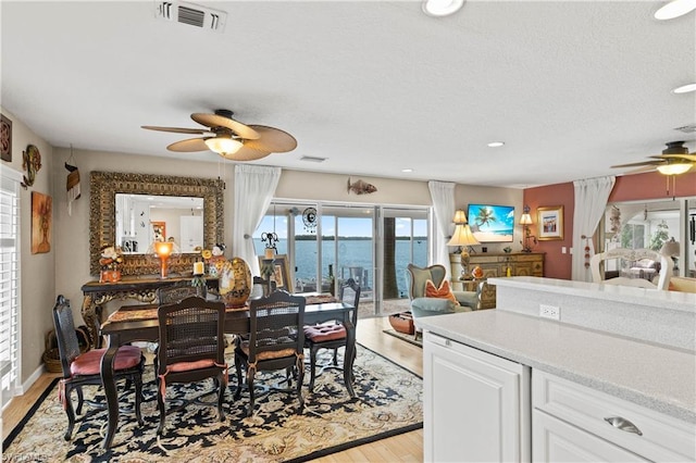 dining area featuring a water view, ceiling fan, and light hardwood / wood-style flooring