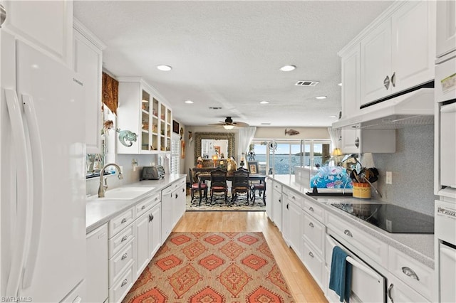 kitchen with light hardwood / wood-style floors, ceiling fan, white refrigerator, and white cabinetry