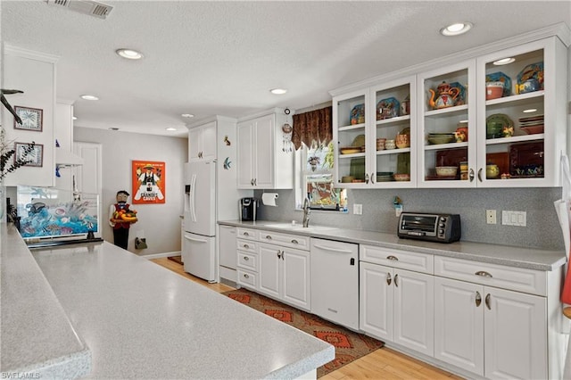 kitchen with white appliances, a textured ceiling, white cabinetry, and light wood-type flooring