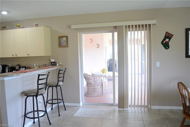 kitchen featuring a kitchen breakfast bar, white cabinetry, and light tile flooring