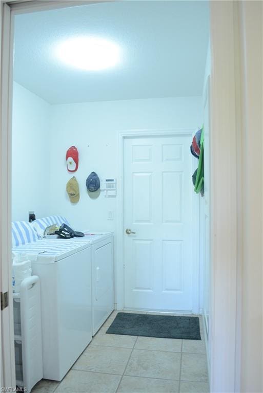 clothes washing area featuring light tile floors and separate washer and dryer