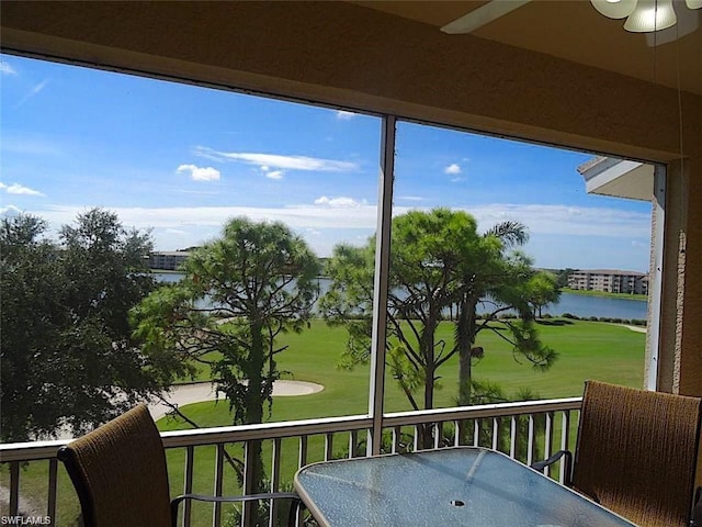 sunroom with ceiling fan and a water view