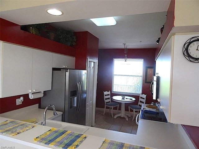 kitchen featuring pendant lighting, light tile floors, stainless steel fridge with ice dispenser, white cabinets, and sink