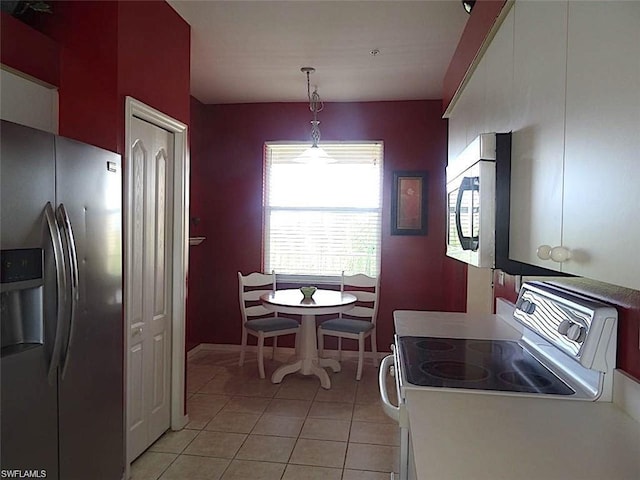 kitchen with stainless steel appliances, light tile flooring, and decorative light fixtures