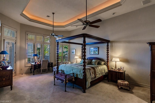 carpeted bedroom with a raised ceiling and ceiling fan