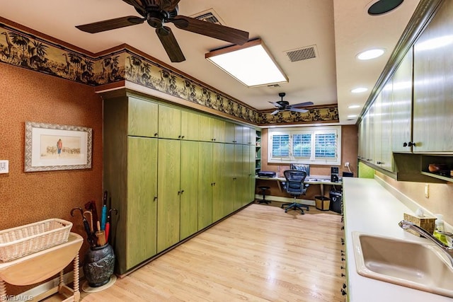 office space with crown molding, ceiling fan, sink, and light wood-type flooring