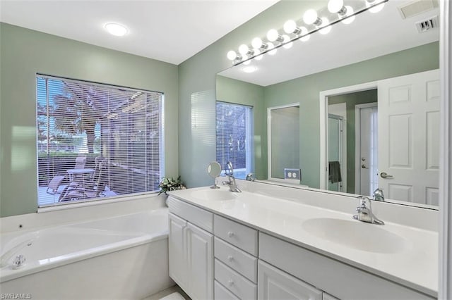 bathroom featuring a healthy amount of sunlight, dual sinks, vanity with extensive cabinet space, and a bathtub