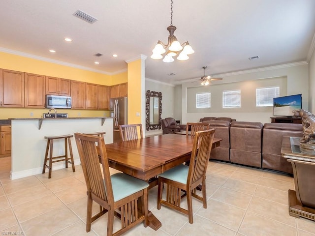 tiled dining area with crown molding, sink, and ceiling fan with notable chandelier