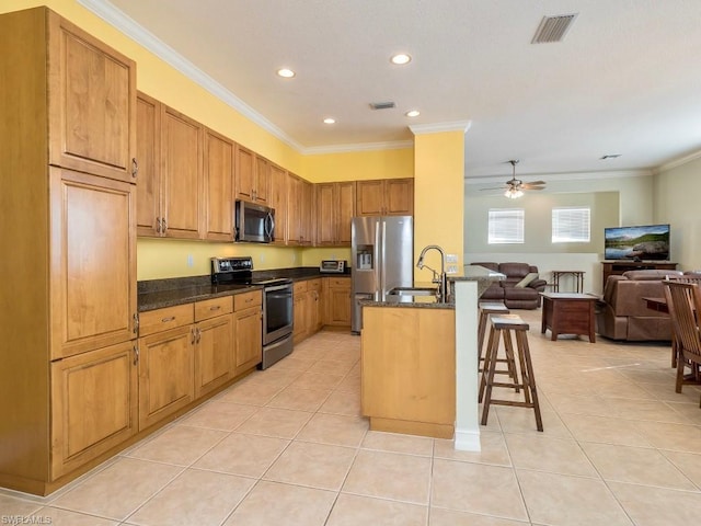 kitchen featuring ceiling fan, light tile floors, dark stone counters, a breakfast bar area, and stainless steel appliances