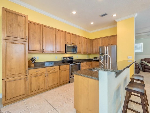 kitchen with sink, crown molding, appliances with stainless steel finishes, a breakfast bar, and a center island with sink