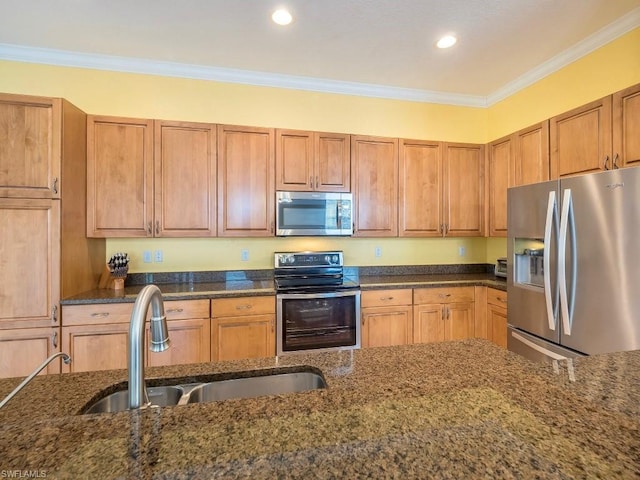 kitchen with dark stone countertops, appliances with stainless steel finishes, crown molding, and sink