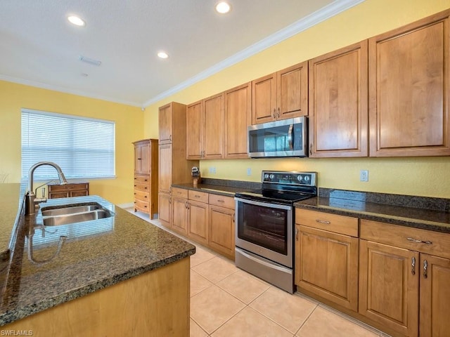 kitchen featuring light tile floors, dark stone counters, ornamental molding, appliances with stainless steel finishes, and sink