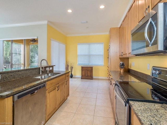 kitchen with stainless steel appliances, light tile floors, dark stone counters, crown molding, and sink