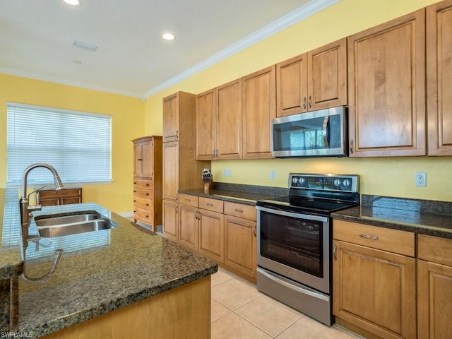 kitchen with sink, light tile floors, dark stone counters, ornamental molding, and appliances with stainless steel finishes