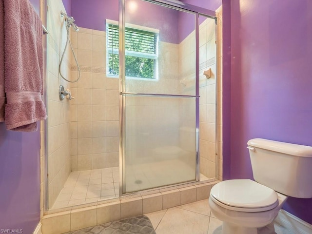 bathroom featuring toilet, tile flooring, and a shower with shower door