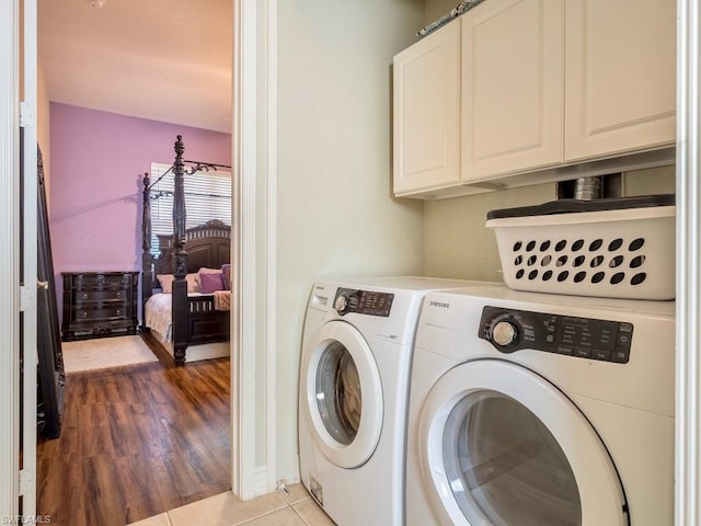 laundry room featuring light hardwood / wood-style floors, cabinets, and washer and dryer