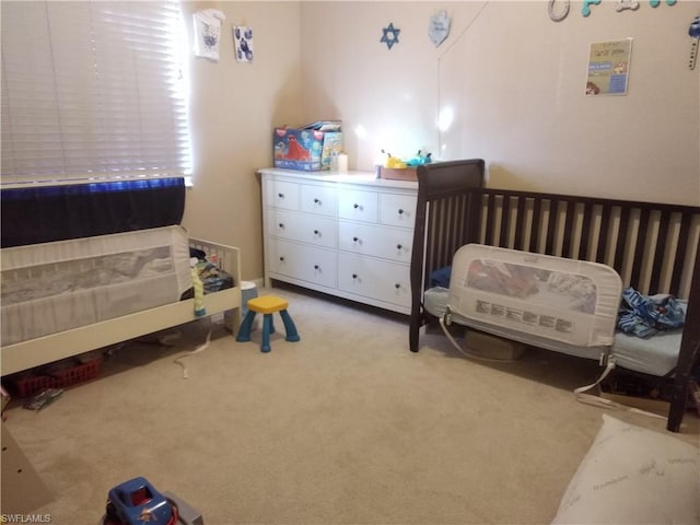 carpeted bedroom featuring a crib