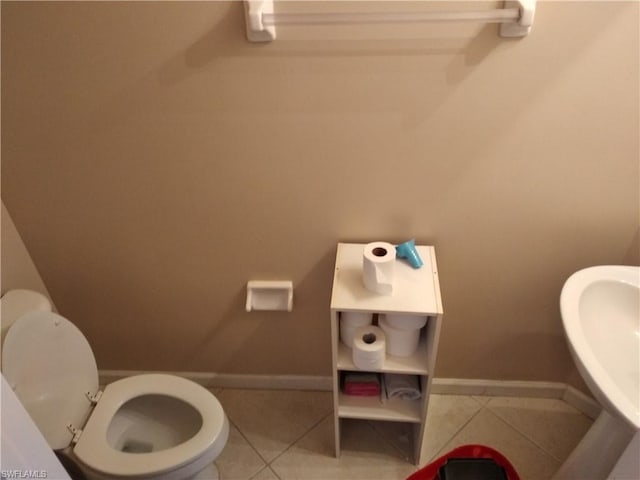 bathroom with toilet, tile floors, and sink