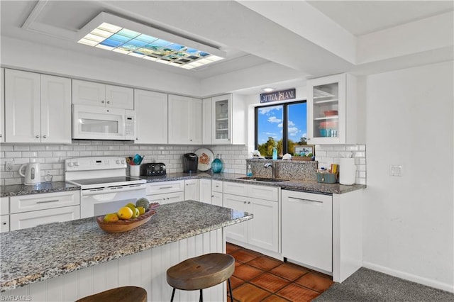 kitchen featuring white appliances, white cabinets, a kitchen breakfast bar, and light stone counters