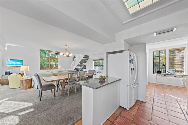 kitchen featuring white cabinets, white fridge with ice dispenser, a chandelier, and a healthy amount of sunlight